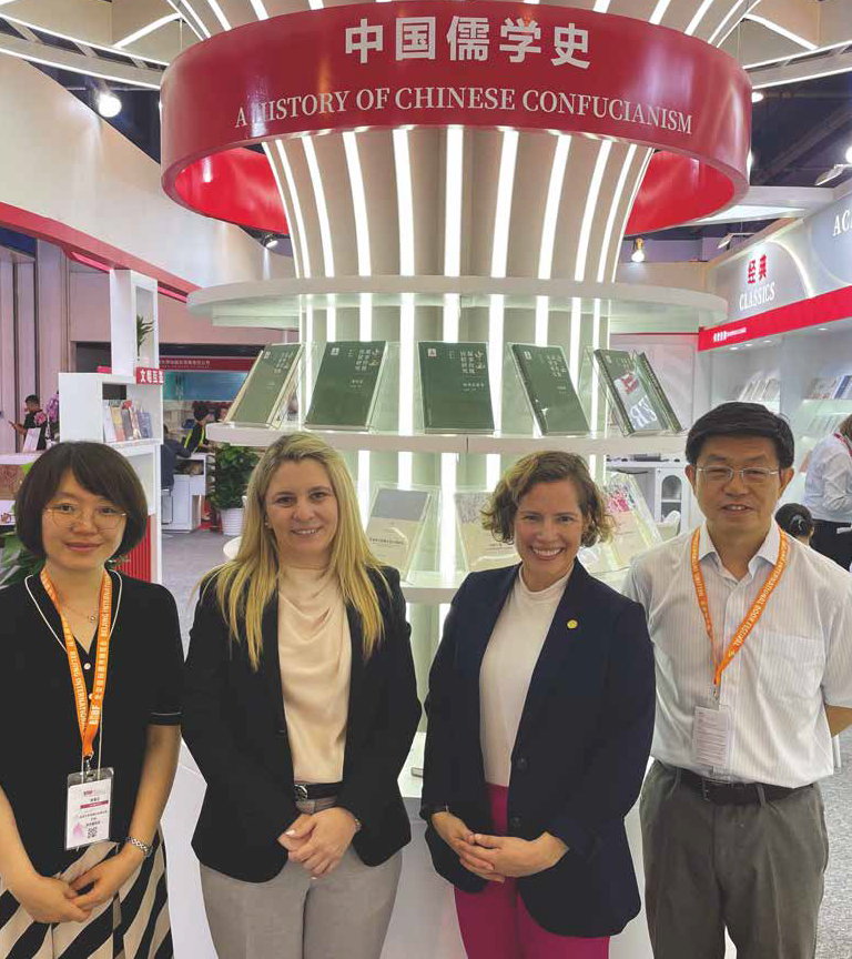 Photo of four people in front of a booth with the title A History of Chinese Confucianism.